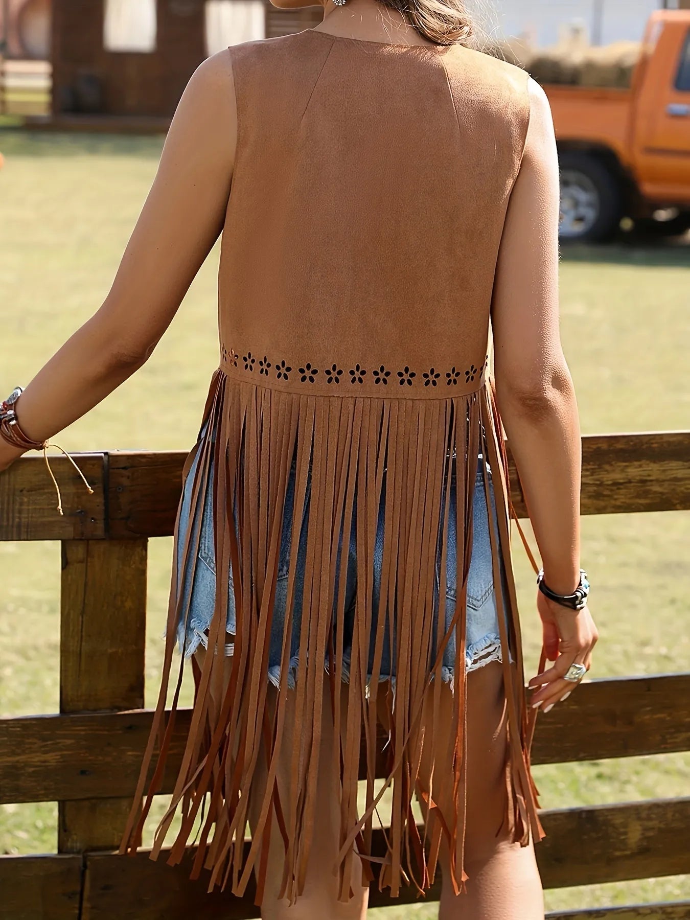 Back View of Woman wearing a Tan Western Cowgirl Fringe Vest Coat over jeans shorts