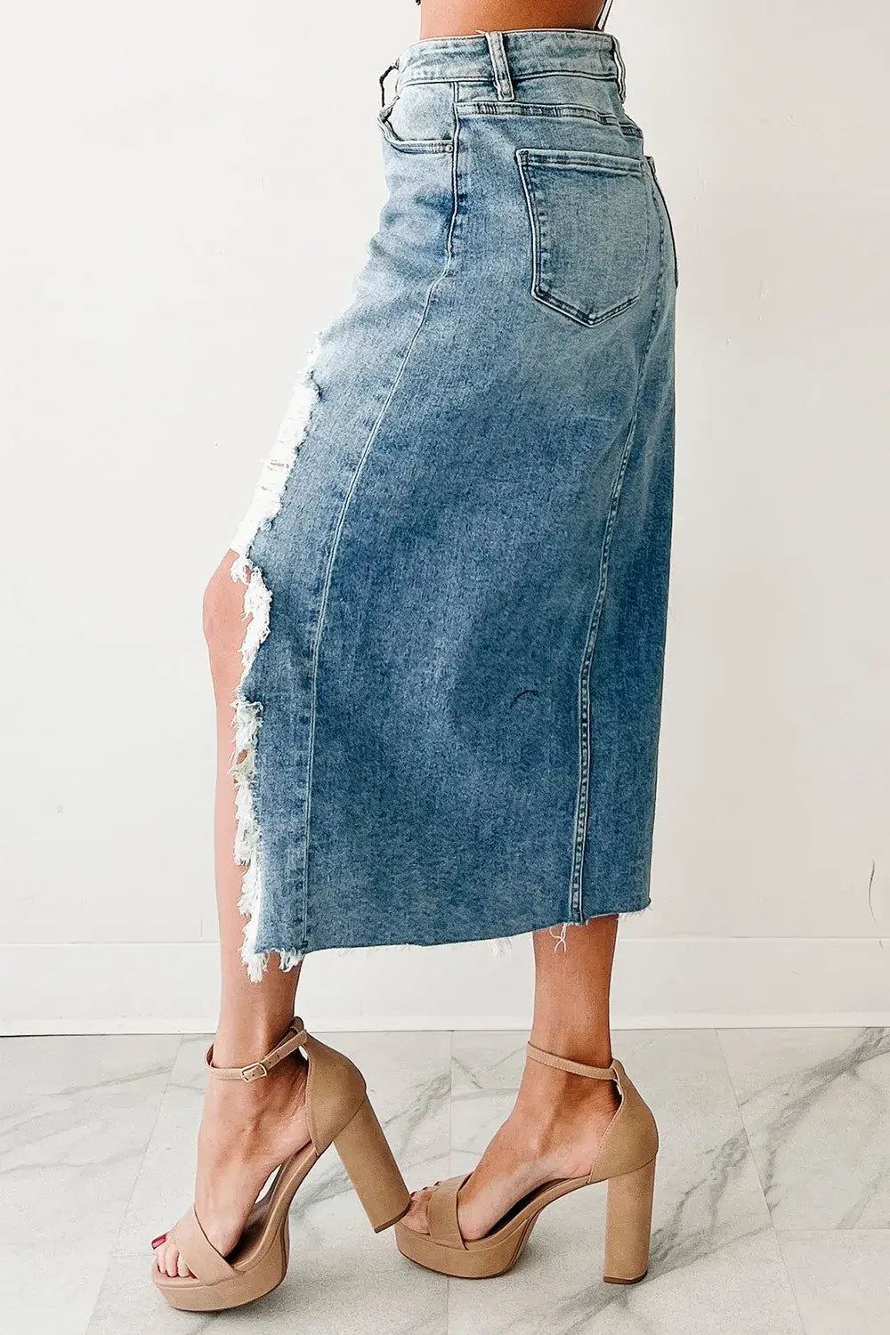 Denim skirt with fringe details worn by a person on a white background