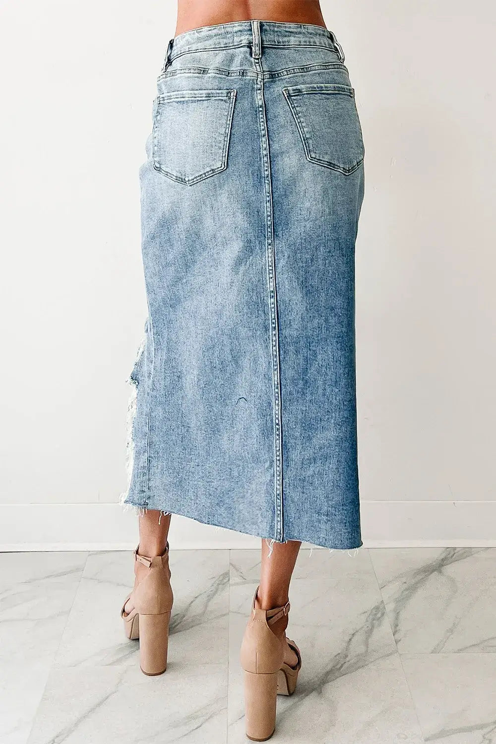 back view of woman wearing a Distressed Asymmetrical Denim Skirt with Frayed Hem