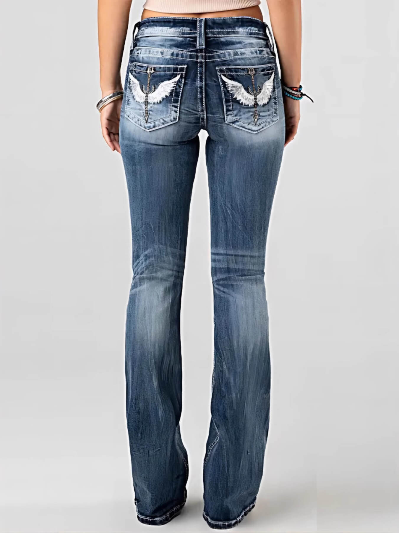 Blue jeans with decorative patches on the back pocket against a gray background