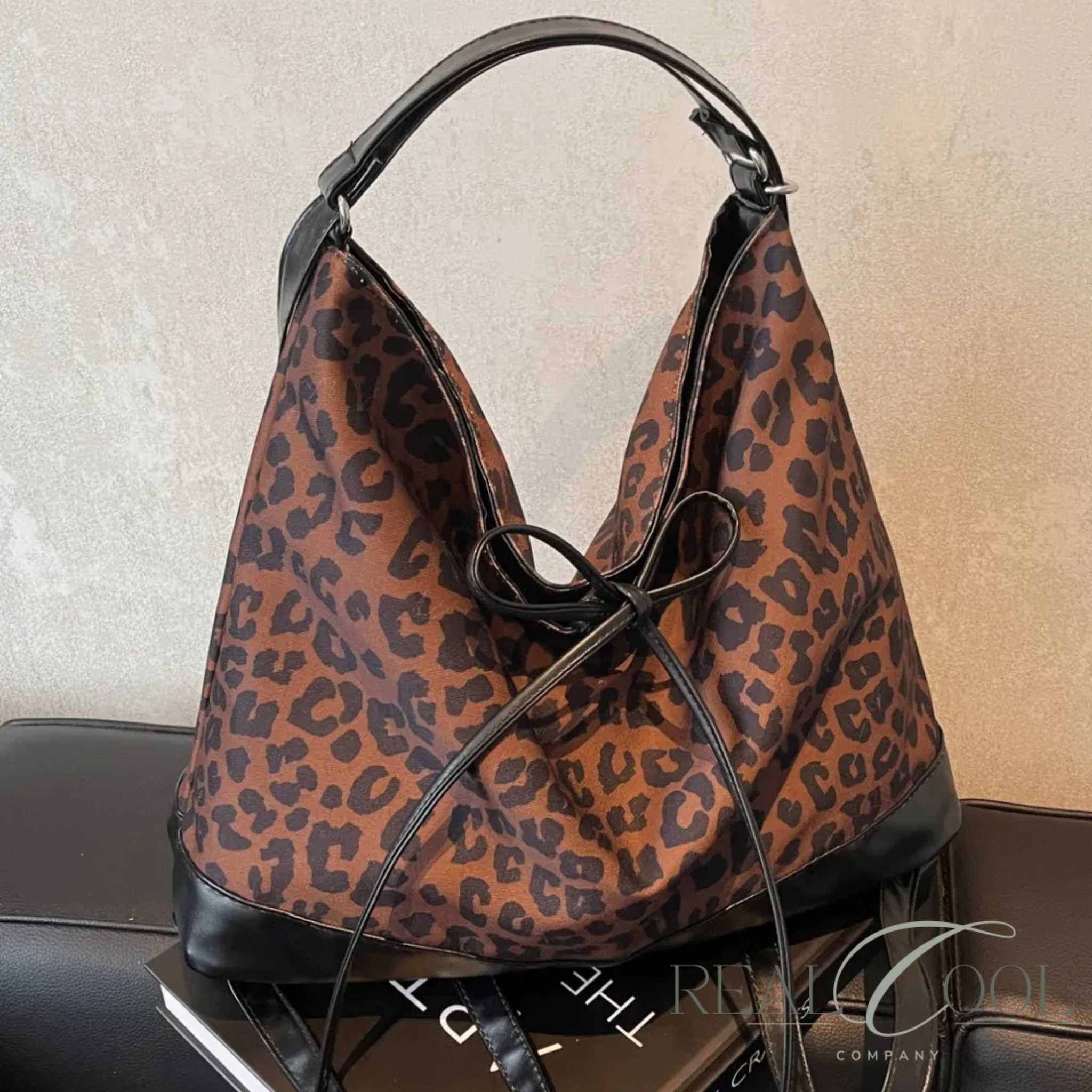 Leopard print handbag with black accents on a sofa