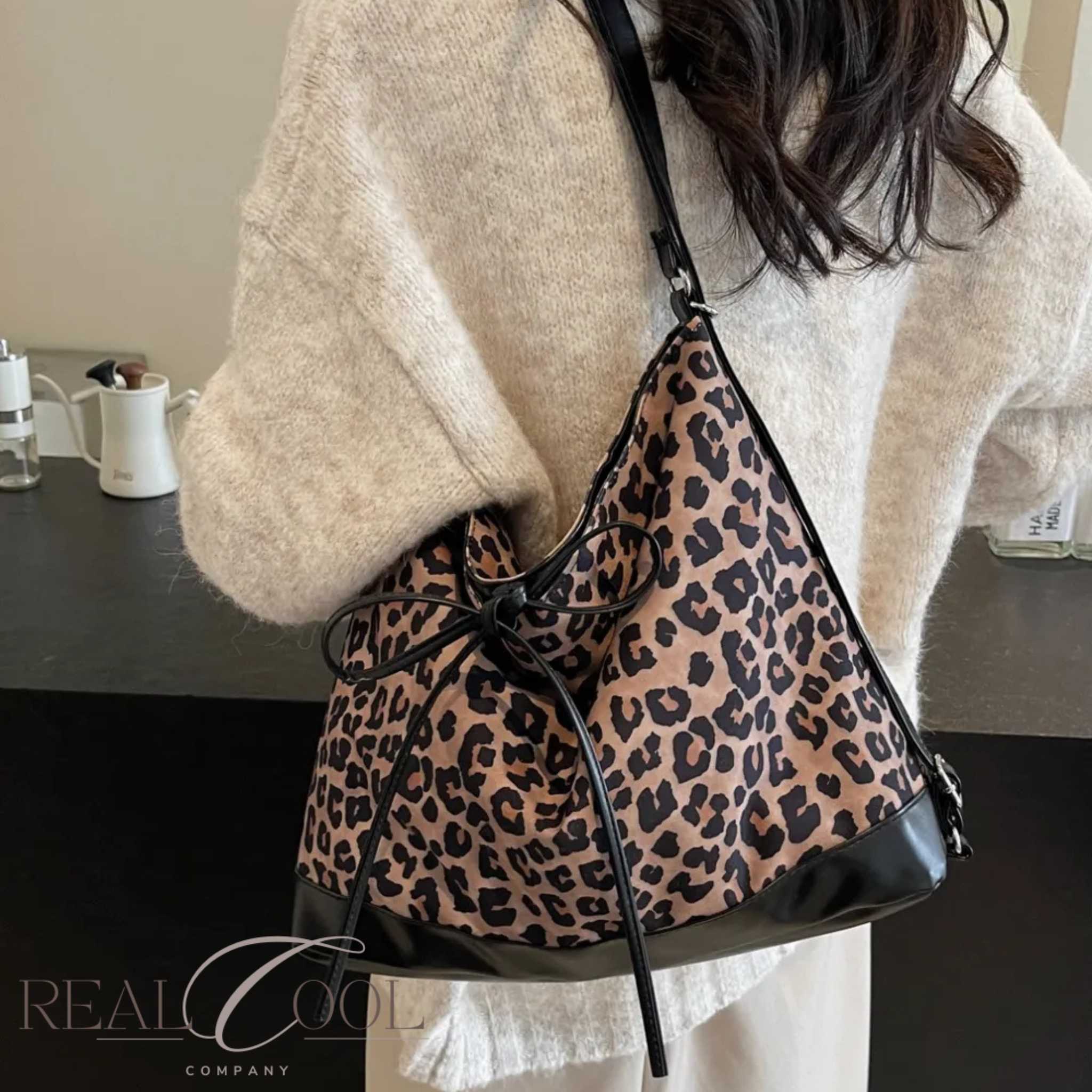 Person wearing a leopard print shoulder bag indoors